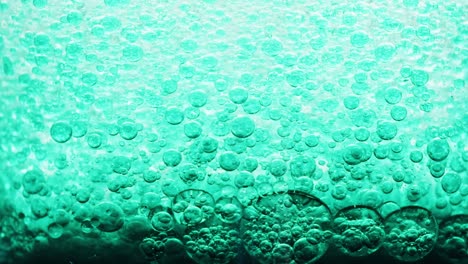 macro shot of many blue bubbles setting on dark ground in water