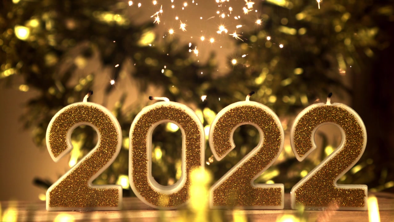 Candele di Felice Anno Nuovo 2022 con stelle filanti dorate e luci festive.