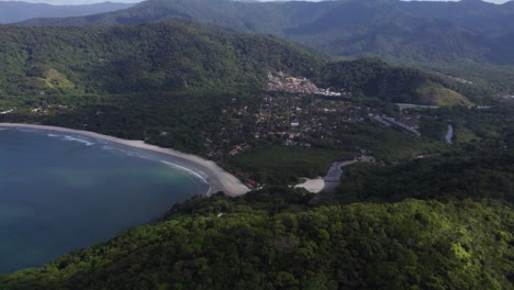 drone diving shot approaching a beach and village, in costa verde, sunny brazil