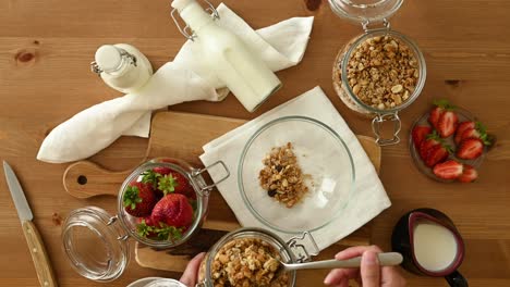 crop person preparing breakfast with granola milk and strawberries