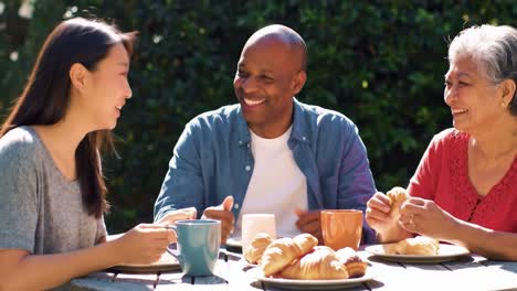 a joyful gathering over breakfast: friends enjoying croissants and warm beverages in a sunlit garden setting