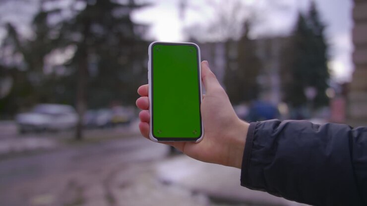 Hand man uses holding a mobile telephone with a vertical green screen background on of street houses people key smartphone technology touch message display