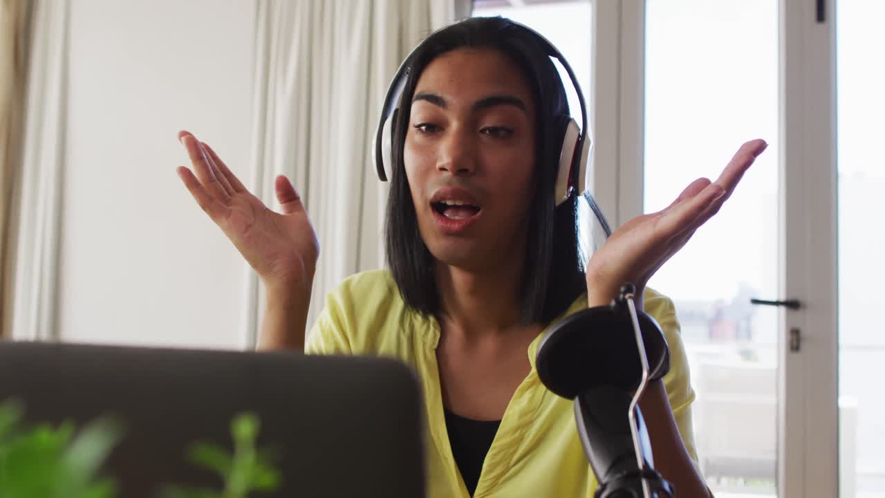 persona de género fluido de raza mixta grabando un podcast usando una computadora portátil en casa