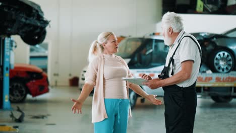 dissatisfied female client argues with a mechanic old man in service shop.