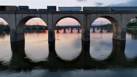 drohnenflug über fluss und brückenbögen während des goldenen sonnenuntergangs