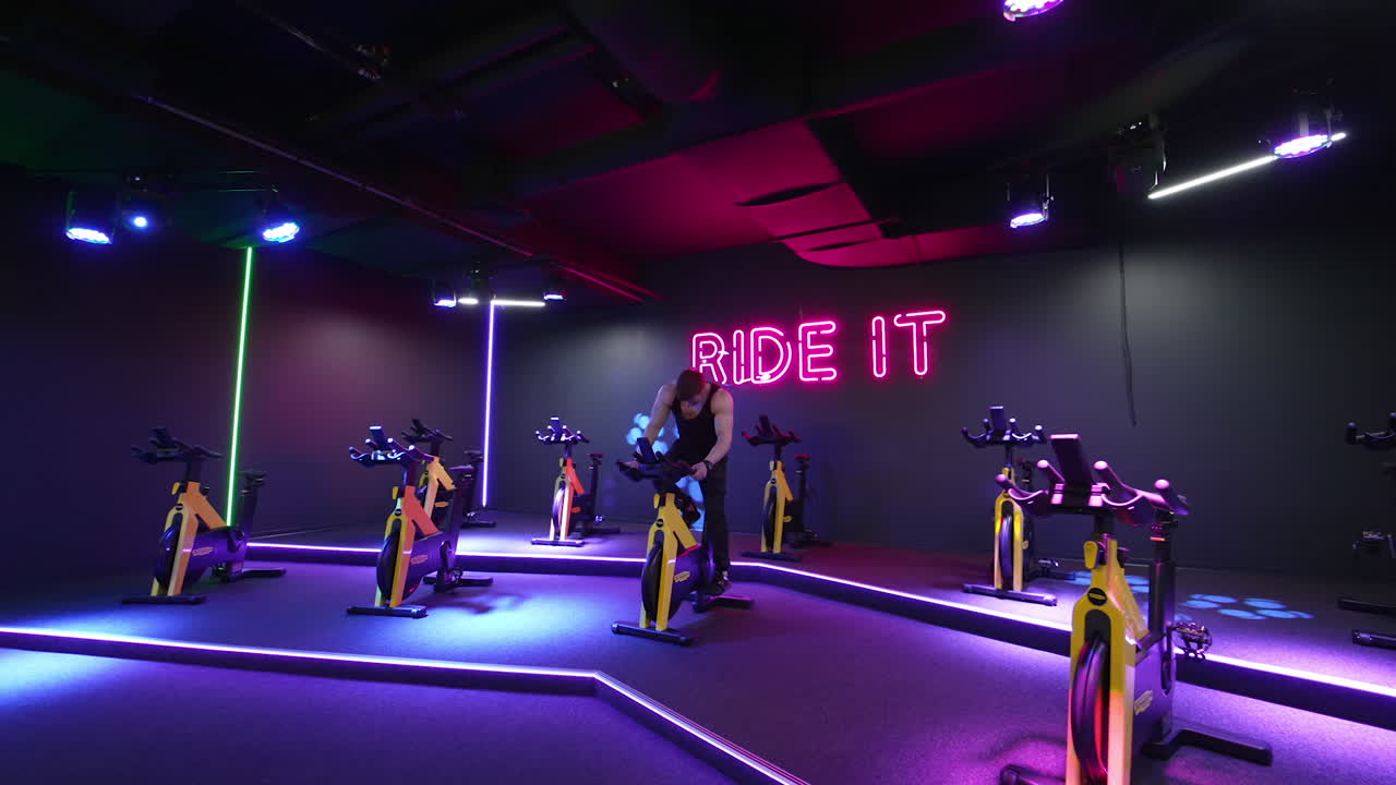 Man training on sports equipment. Athletic young man doing spinning at gym