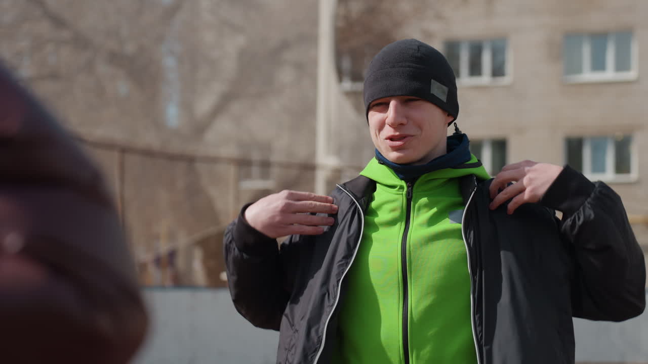 Спортивное неоновое худи на человеке, демонстрирующем выразительные движения и уверенность; спортсмен в энергичной городской одежде принимает уверенную позу, демонстрируя яркий наряд и жесты