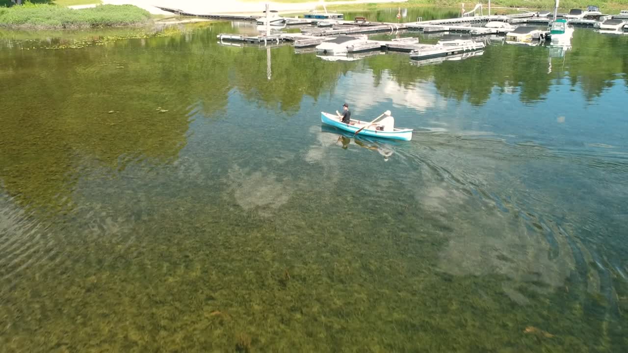 두 남자가 배경에 도크가 있는 호수에서 카누를 타고 있다