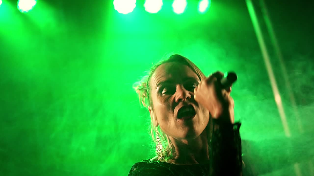 disparo medio de una cantante talentosa tocando un concierto con su micrófono en el escenario con un espectáculo de luces y una actuación impresionante