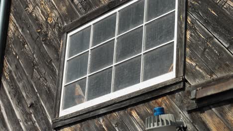 Panning-down-from-the-window-of-a-old-wooden-sided-barn-to-the-concrete-stone-wall-below