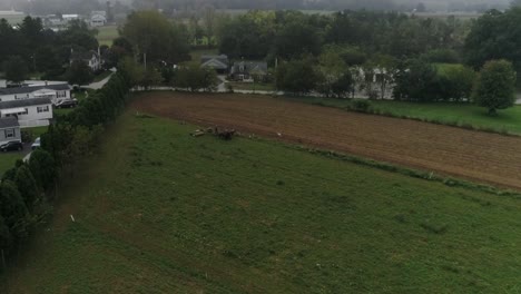 Drone-Ariel-Vista-De-Tierras-Agrícolas-Amish-Y-Granjero-Amish-Cosechando-En-La-Niebla