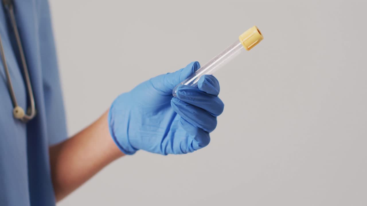 video de una doctora biracial sosteniendo un tubo de ensayo sobre un fondo azul