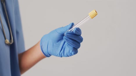 Video-of-biracial-female-doctor-holding-test-tube-on-blue-background