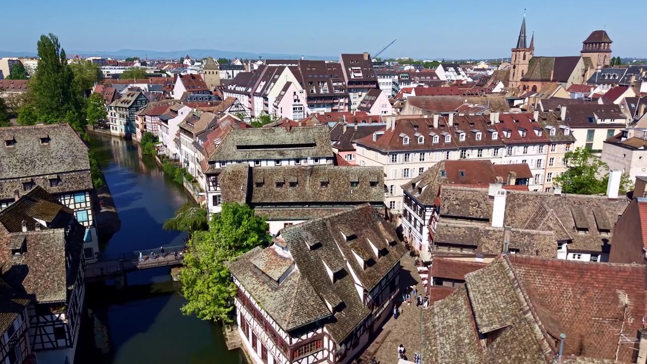 Schwenkender Drohnenflug über charmante Fachwerkhäuser und den ruhigen Ill-Flusskanal prägt das Wohnviertel Quai des Moulins in Straßburg mit der Fasanenbrücke, Petite France, Frankreich.