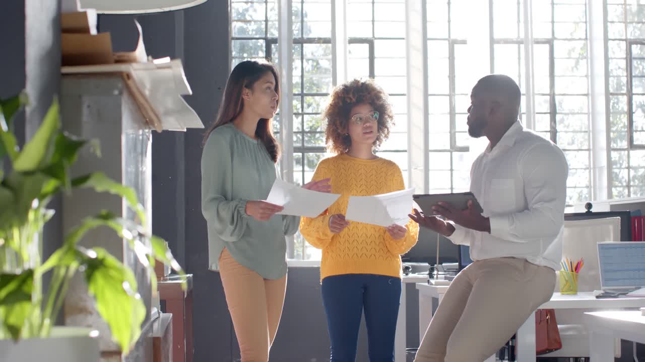 diversos colegas con documentos y tableta discutiendo el trabajo en una oficina soleada, cámara lenta