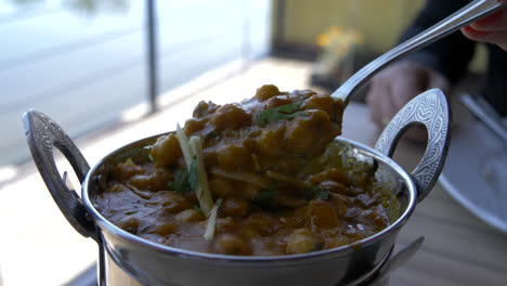 cámara lenta de una cuchara en un plato de curry humeante caliente