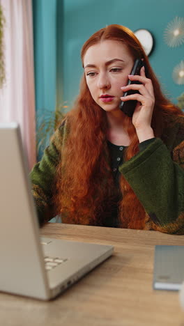 happy excited redhead woman making phone conversation call with client or colleague sitting at home