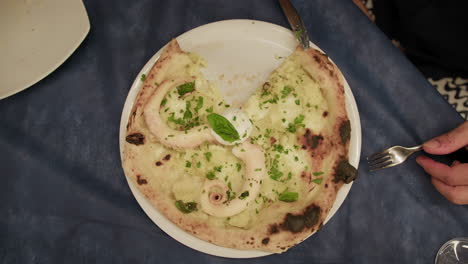 man grabbing a slice of gourmet pizza with octopus at the restaurant