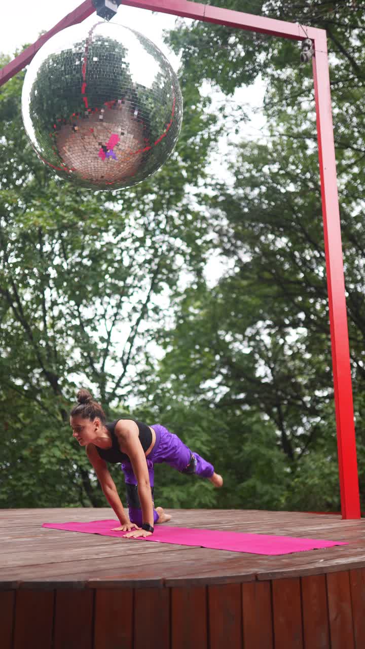 mujer realizando yoga en el parque con una pelota de discoteca