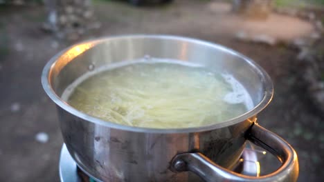 slomo close-up of boiling, steaming water with spaghetti in a cooking pan