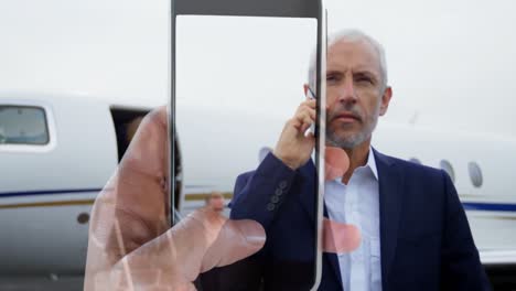 video compuesto de la mano sosteniendo un teléfono inteligente sobre un hombre de negocios caucásico hablando en teléfono inteligente