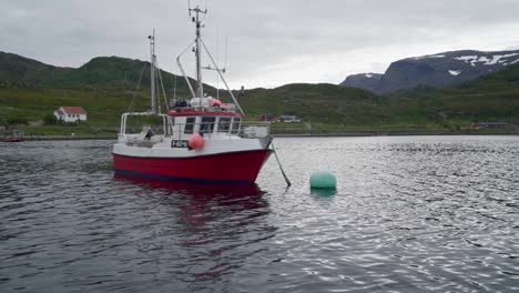 fishing boat anchored in the ocean near traditional fishing village in norway