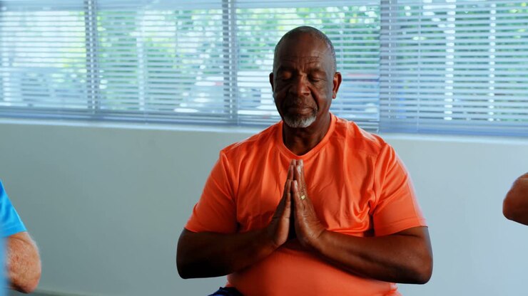 vista frontal de un hombre anciano afroamericano activo realizando yoga en un estudio de fitness 4k