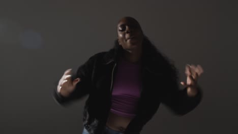 Studio-Portrait-Shot-Of-Young-Woman-Dancing-With-Low-Key-Lighting-Against-Grey-Background-10