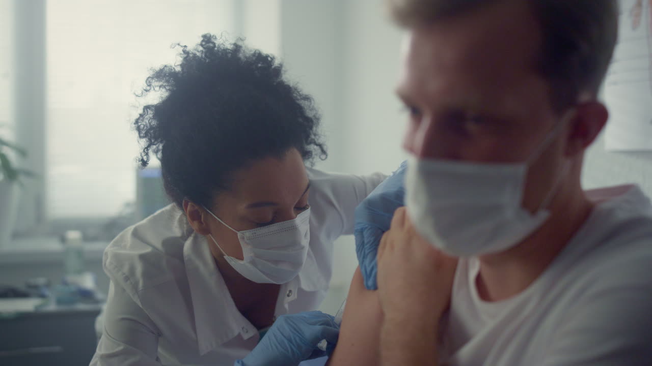 Doctor injecting vaccine patient shoulder in health clinic. Vaccination concept.