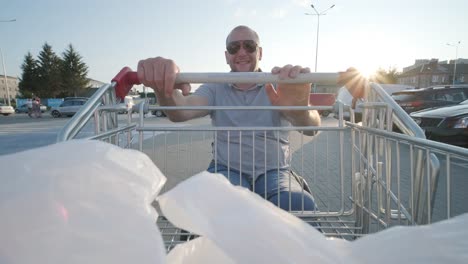 man with disabilities in wheelchair pushing cart in front of himself at supermarket parking