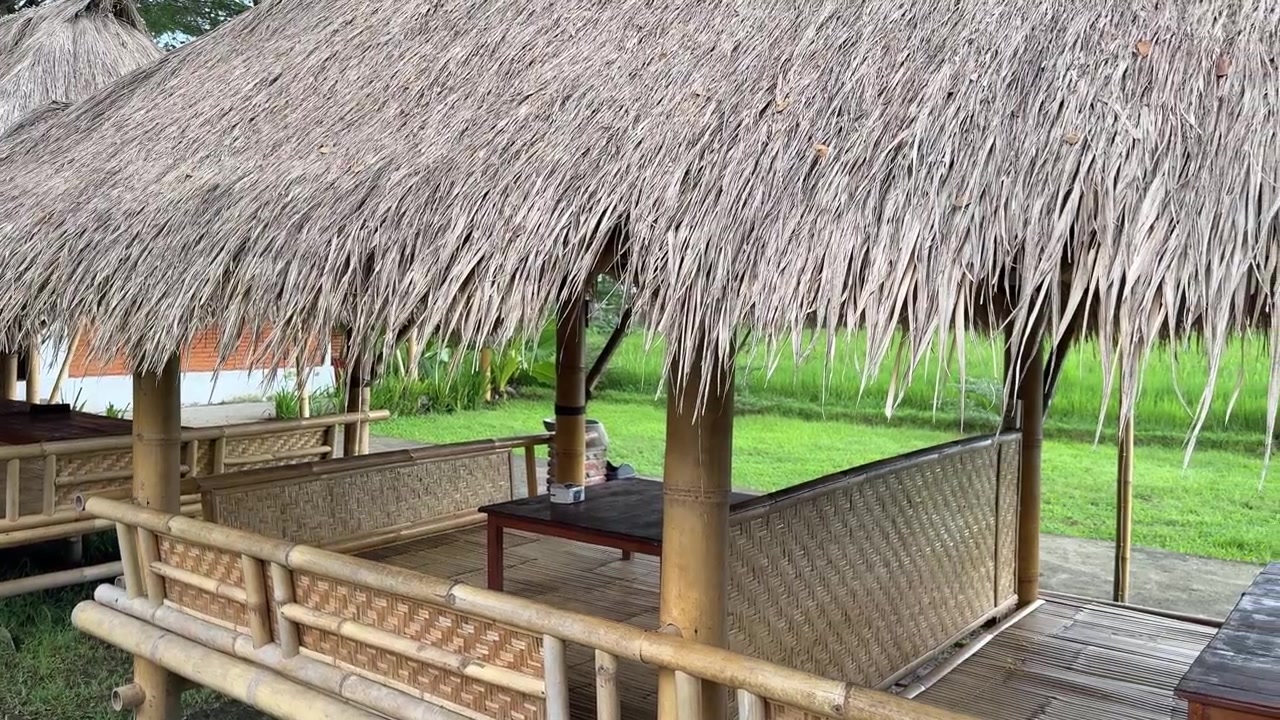 Capanne tradizionali di bambù con tetti di paglia in un paesaggio verde.
