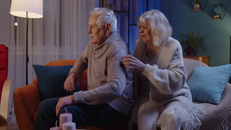 portrait of angry mature grandparents couple quarreling in evening at home sofa, crisis, conflicts