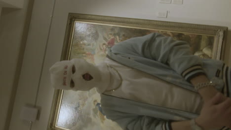 man in mask in front of paintings