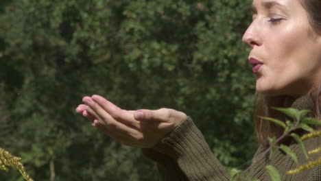 woman in the meadow blows a little fluff from her palms