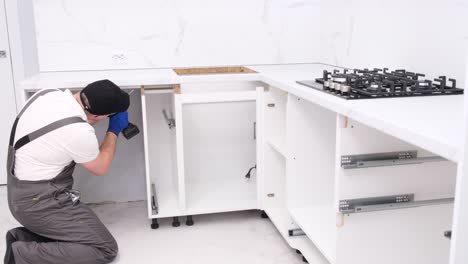 handyman installs furniture and appliances in the kitchen with special tools indoors handyman installs furniture and appliances in the kitchen with special tools indoors the concept of furniture restoration and assembly