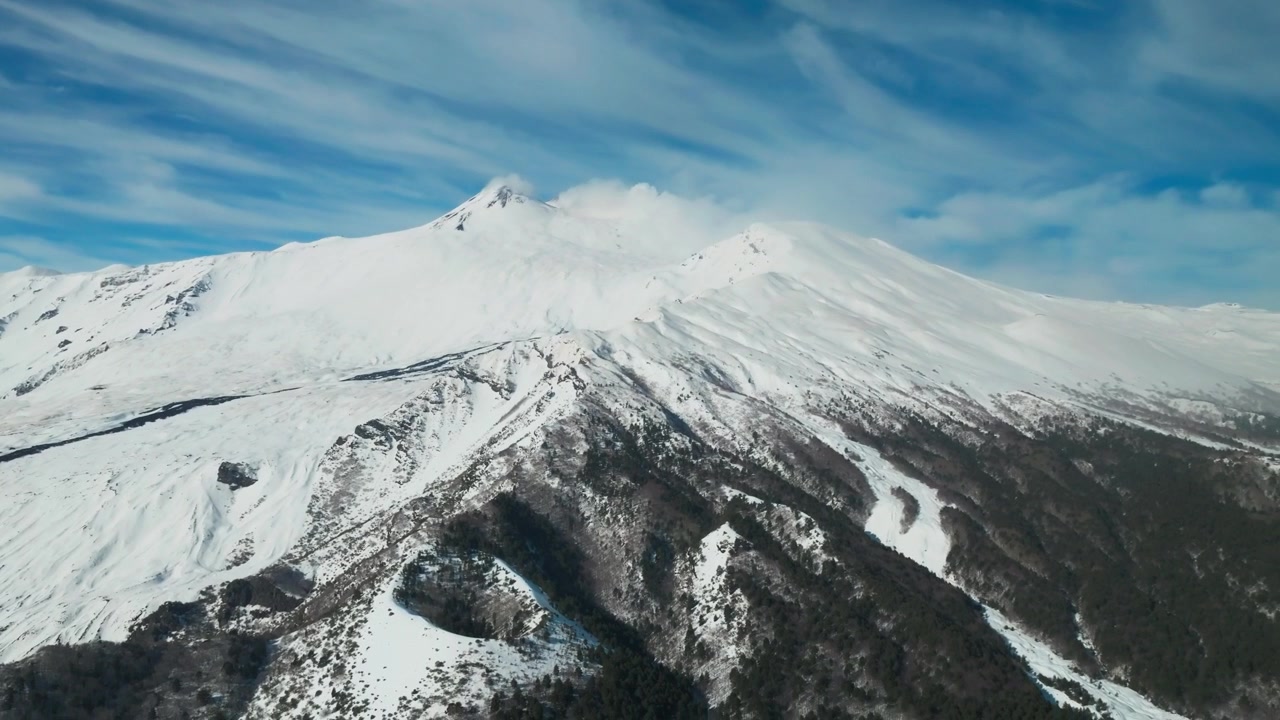 Monte Etna, Sicilia, Italia, ripresa con drone di un cono vulcanico e pendii innevati in una giornata di sole