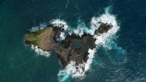 volcanic basalt island surrounded by rough blue water of atlantic ocean, aerial