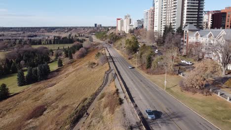 Panorama-Aéreo-Desde-La-Autopista-Hasta-Los-Condominios-Residenciales-De-Las-Torres-Del-Valle-Junto-Al-Borde-Del-Parque-En-Un-Cielo-Azul-Claro-Día-De-Otoño-Con-Tráfico-Ligero-Y-Escaleras-Que-Conducen-A-Caminos-De-Campos-De-Golf-Con-Corredores-Y-Parejas