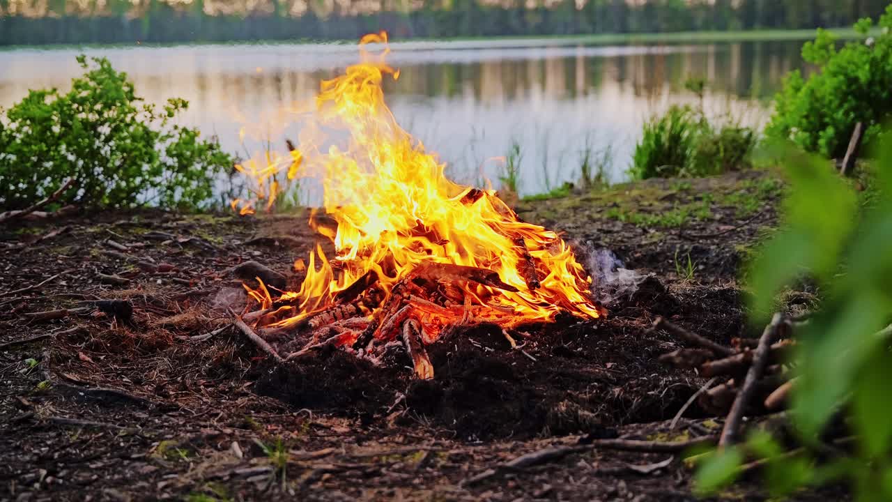 Slow Motion Shot Of Firewood Flames By Lake Showing Daily Life In Warming World