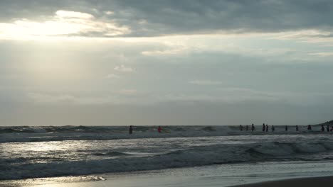 a group of swimmers entering the ocean for a sunrise morning training session on an overcast day at the popular burleigh on the gold coast australia