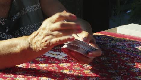 elderly hands shuffling pack of playing cards at summer garden table