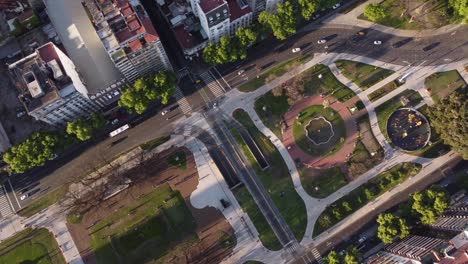 Aerial-tracking-shot-of-driving-cars-and-bus-on-road-beside-Congress-Square-in-Buenos-Aires-during-sunset-time---Top-down-view