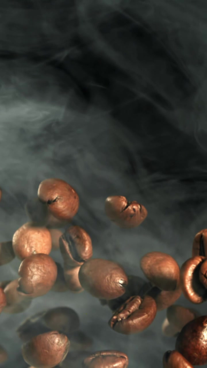Chicchi di caffè tostati che fluttuano verso l'alto al rallentatore con fumo