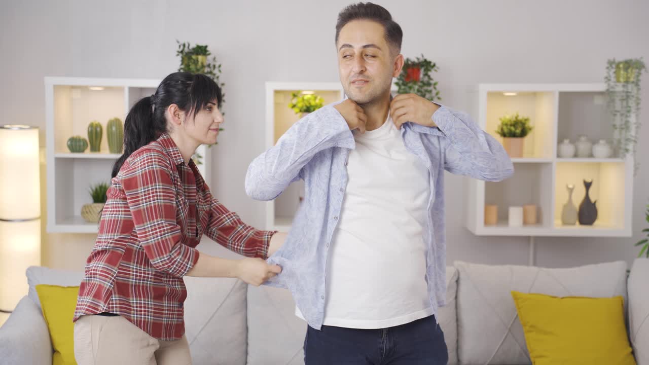 남편에게 옷을 입히는 여자.