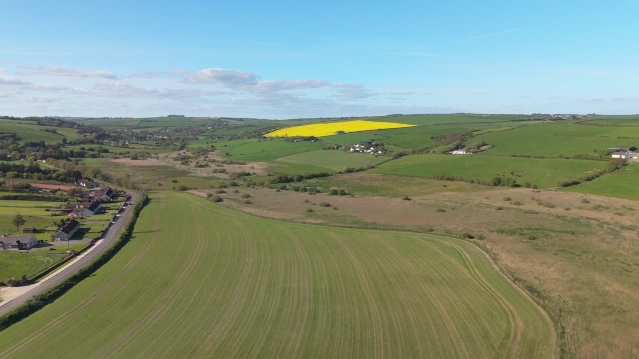 Green hills, and yellow fields with crops. Drone aerial panorama over Ireland