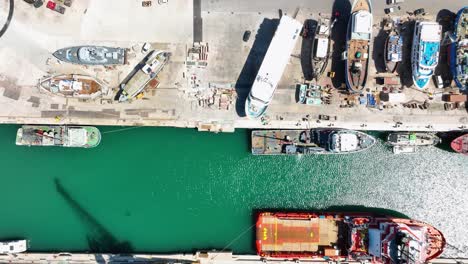 aerial drone shot flying slowly sideways with a top down view of ships in a boat yard