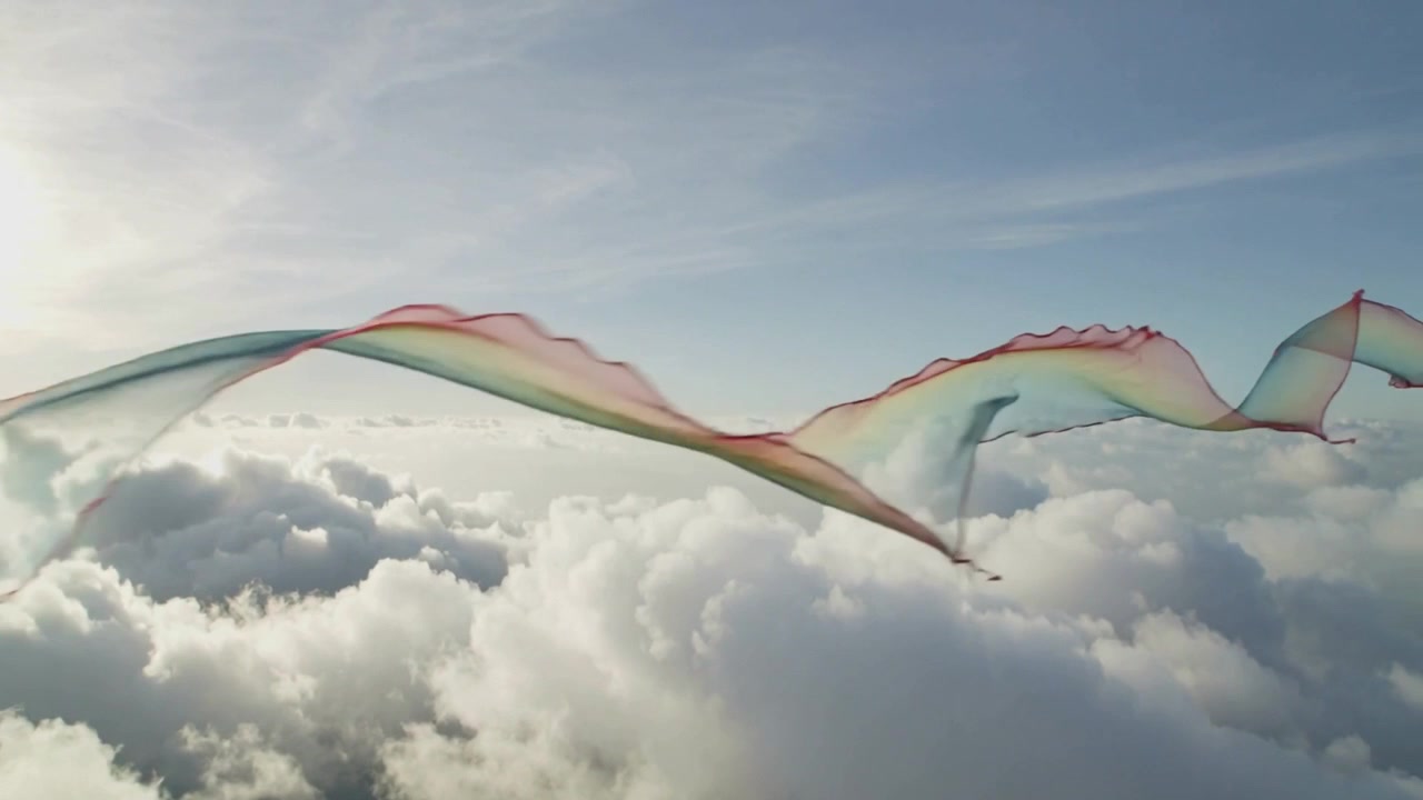 Nastro arcobaleno velato che fluttua sopra le cime delle nuvole, con il sole che retroillumina i bordi scintillanti.
