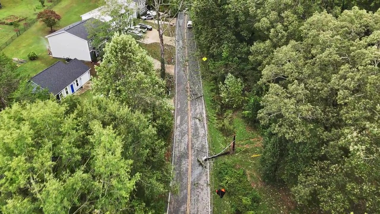Aerial drone footage in Greenville, South Carolina of damage from Hurricane Helene with trees and power lines fallen across road and driveway