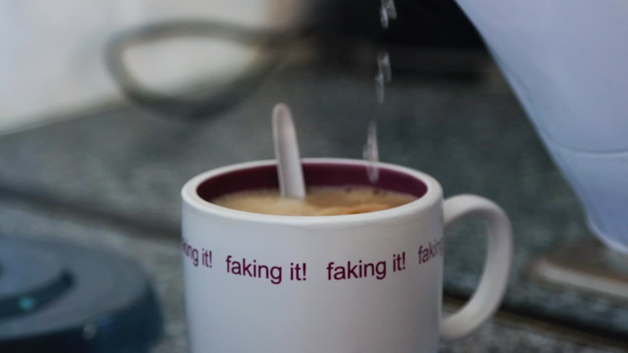 Pouring boiling water from the kettle into cup for making coffee
