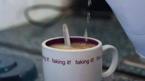 pouring boiling water from the kettle into cup for making coffee